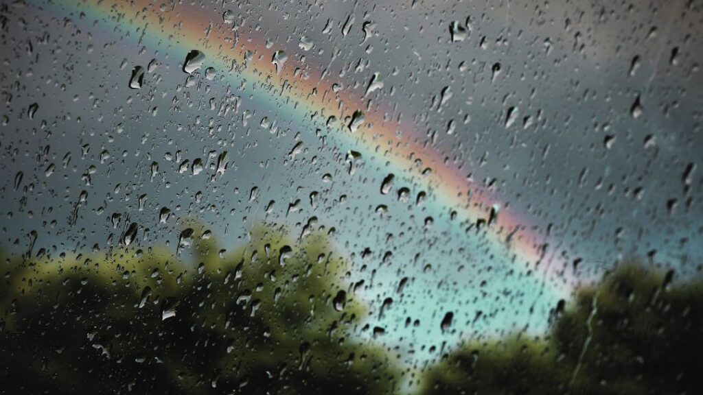 Cómo aliviar el dolor de espalda en días de lluvia Alivio del dolor de espalda en días de lluvia: arcoíris aparece tras una ventana un día lluvioso