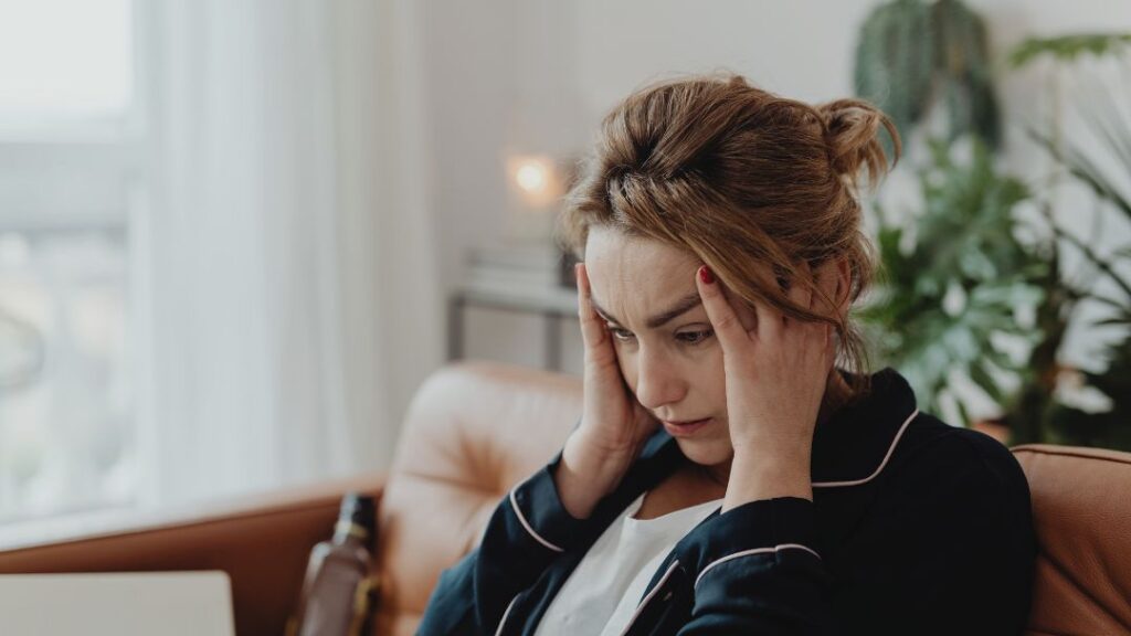 El estrés, la ansiedad y/o la falta de sueño influyen directamente en la percepción de los síntomas Persona tensionada con las manos en el cuello y la espalda, ilustrando cómo el estrés y la carga emocional provocan dolor de espalda.